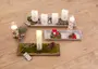 Set med dekorativa LED-ljus med fjärrkontroll, placerade på träbrickor med mossa, kottar, konstgjorda svampar och juldekorationer, perfekt för vinter- eller julinredning.