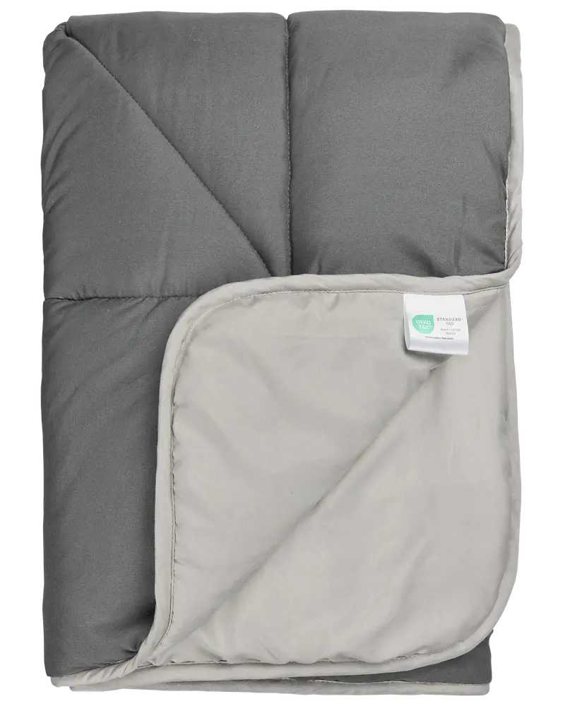 Grå og lysegrå dyne med quiltet syning, blød tekstur og hjørnemærke med materiale- og plejeinstruktioner. Velegnet til sengetøj, giver varme og komfort.