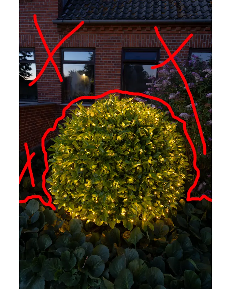 Utomhusbuske täckt med varmvita LED-ljusslingor, ger ett glödande dekorativt intryck. Perfekt för trädgårds- eller högtidsdekoration. Ljuset är jämnt fördelat.