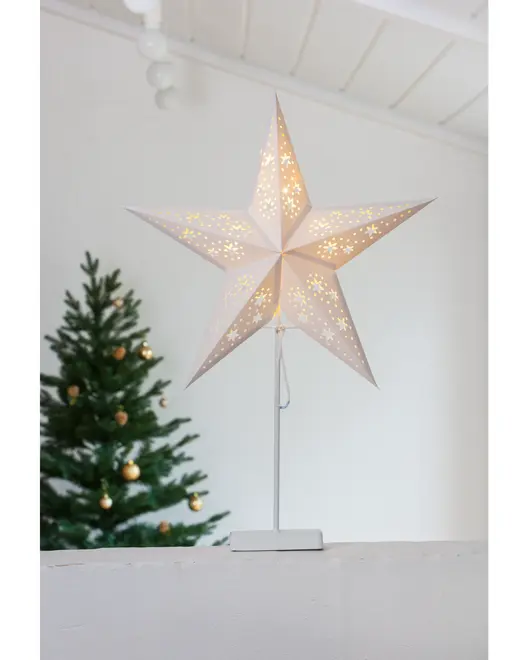 Oplyst hvid papirstjernelampe med fine udskæringer, monteret på en slank hvid fod. Perfekt til juledekoration, udsender varmt lys. Synlig ledning, moderne festligt design.
