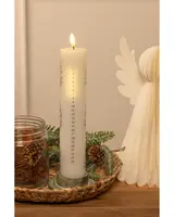 Högt vitt adventsljus med numrerade dagar, brinner upptill. Står på en flätad bricka med kottar, grankvistar och en dekorativ vit ängel bredvid.