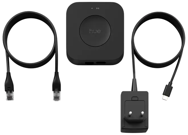 Philips Hue Bridge sæt med sort firkantet hub, Ethernet-kabel, USB-C strømkabel og stikadapter. Nødvendig til smart belysningsstyring og forbindelse med Philips Hue produkter.