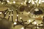 Varme hvide lyskæder flettet i granranker med en reflekterende glasjulekugle, som skaber en hyggelig festlig juledekoration.