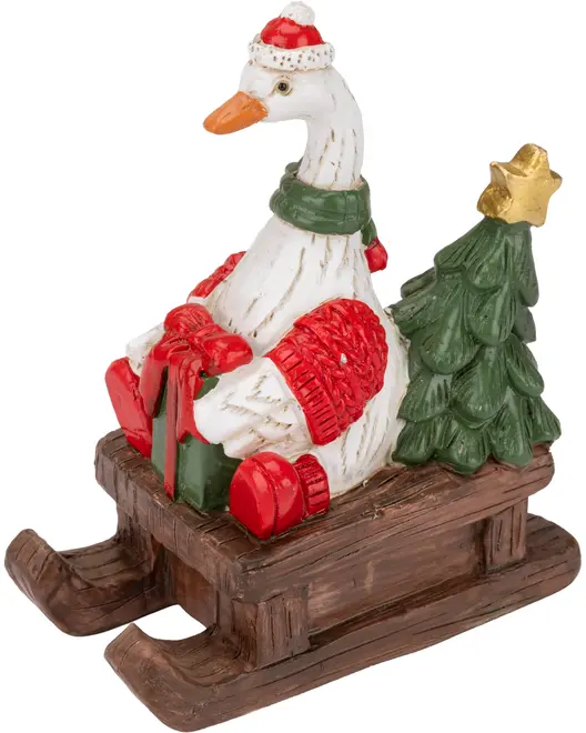 Festiv hvid gåsefigur med nissehue og grøn tørklæde, siddende på en træslæde med røde gaver og et lille juletræ.