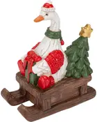 Festiv hvid gåsefigur med nissehue og grøn tørklæde, siddende på en træslæde med røde gaver og et lille juletræ.