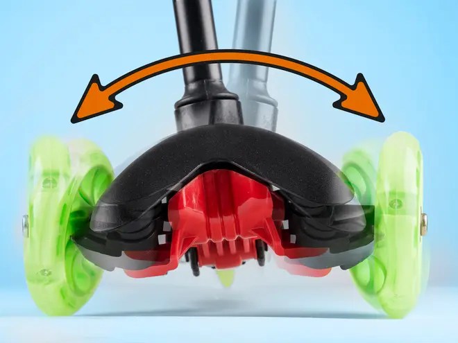 Nærbillede af løbehjulets forhjul og styremekanisme, der viser vippefunktion med grønne hjul, sort og rød bund samt orange pil for drejebevægelse.