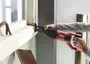 Röd och svart SKIL tigersåg med ergonomiskt handtag, används för att såga i ett fönsterkarm. Passar för rivning, renovering och träarbete.
