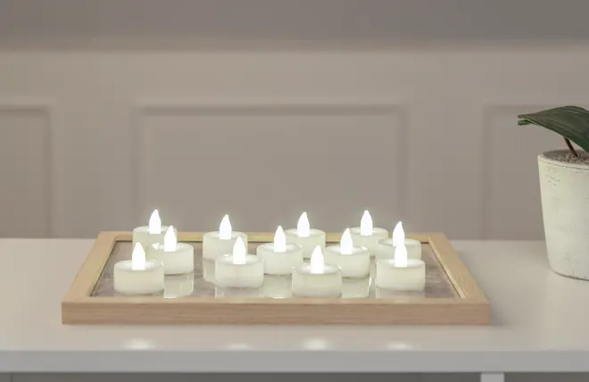 Sæt med tolv hvide LED fyrfadslys med realistisk flammeeffekt, arrangeret på en træbakke. Batteridrevne, flammeløse, sikre til indendørs brug, perfekte til dekoration eller stemningsbelysning.