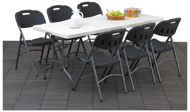 Rektangulært hvidt klapbord med seks sorte klapstole. Bordet har metalben, stolene har formede rygge. På bordet står en tekande, frugtkurv og dåsedrikke.