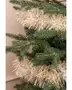 Kunstigt juletræ med naturtro grønne grene, pyntet med en tyk, skinnende sølv- og guldfarvet guirlande, der er viklet rundt om grenene for et festligt udtryk.
