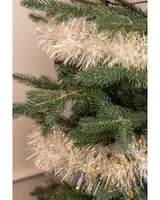 Konstgjord julgran med naturtrogna gröna grenar, dekorerad med ett tjockt, glittrande silver- och guldfärgat glitter runt grenarna för en festlig känsla.