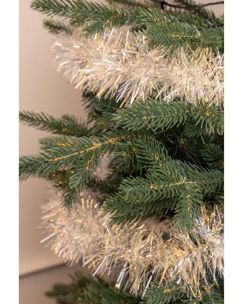 Konstgjord julgran med naturtrogna gröna grenar, dekorerad med ett tjockt, glittrande silver- och guldfärgat glitter runt grenarna för en festlig känsla.
