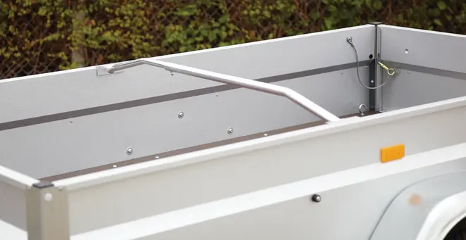 Sølvfarvet aluminiums-anhænger med høje sidepaneler, hjørnebeslag og en buet støttearm.