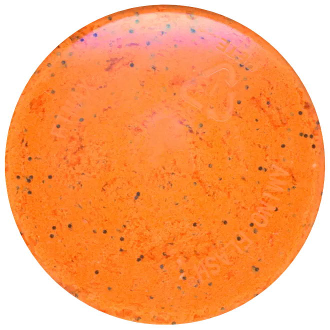 Rund, fast orange shampoo-bar med små sorte prikker. Glat, let blank overflade. Miljøvenligt og plastfrit alternativ til flydende shampoo til hårvask.